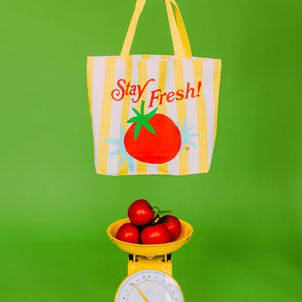 Stay Fresh Tomato Market Tote, yellow striped tote reading Stay Fresh held above a yellow scale of tomatoes on green