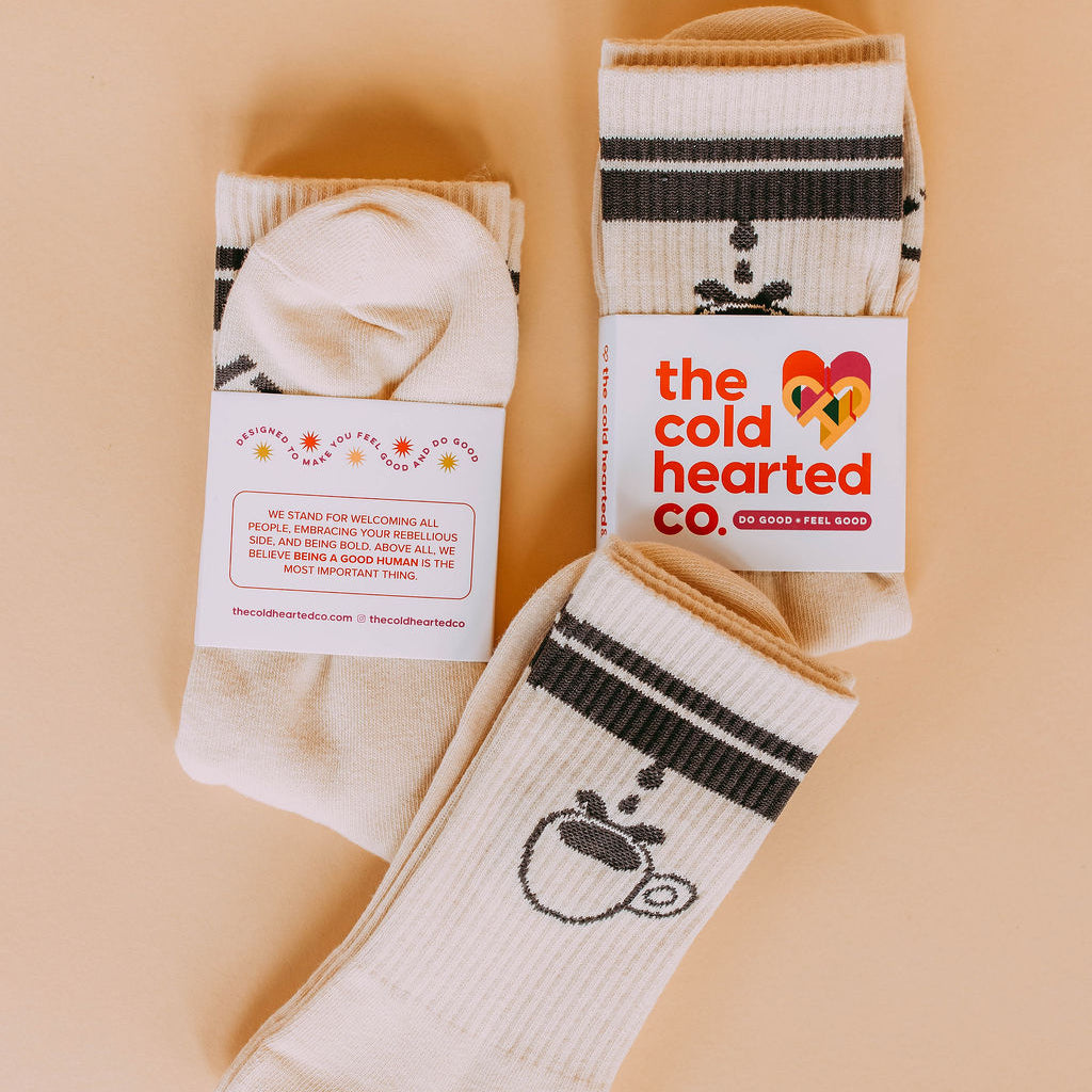 Coffee Cup Drip Socks, cream striped coffee cup socks with brand packaging labels, flat lay on peach background