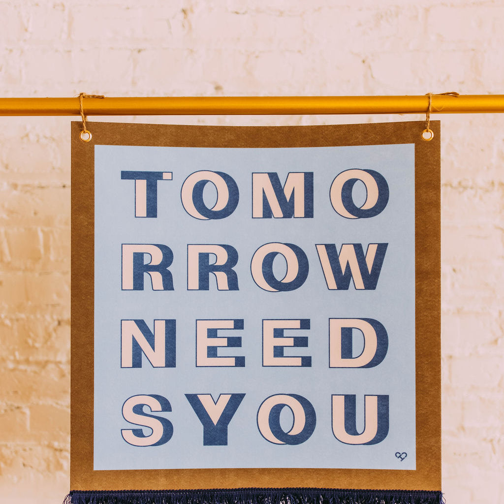 Tomorrow Needs You Pennant, blue felt banner with navy Tomorrow Needs You lettering and fringe, hung on a brass rod
