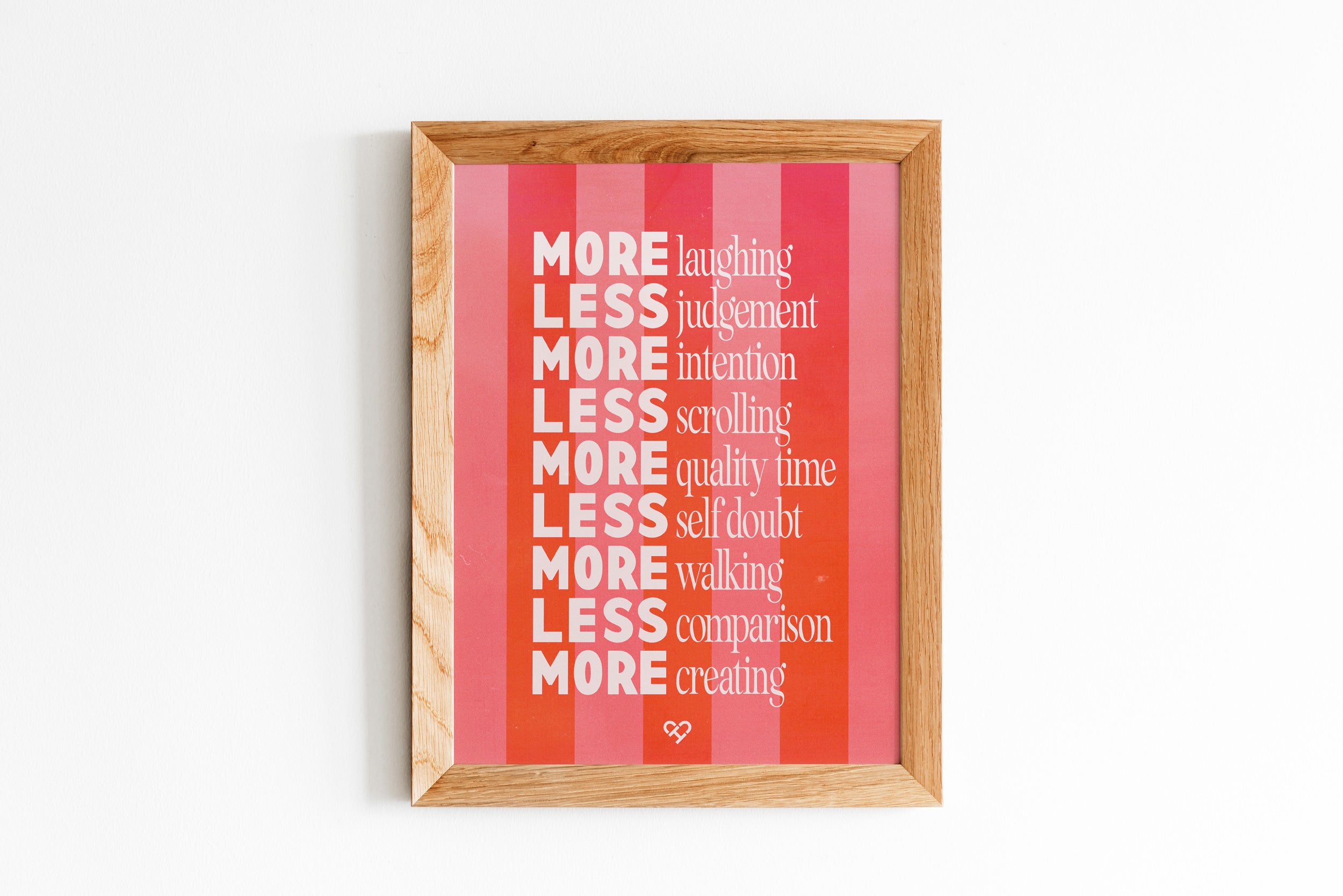 More or Less Print, framed pink and red striped print listing More laughing, Less judgement and more, on a wall
