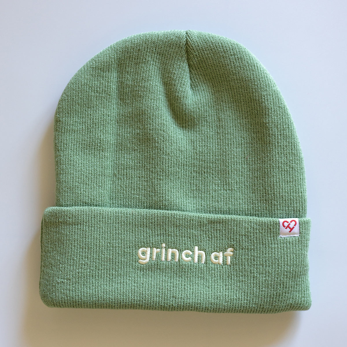 Grinch AF Beanie, sage green cuffed knit beanie with cream grinch af embroidery and a small heart logo tag