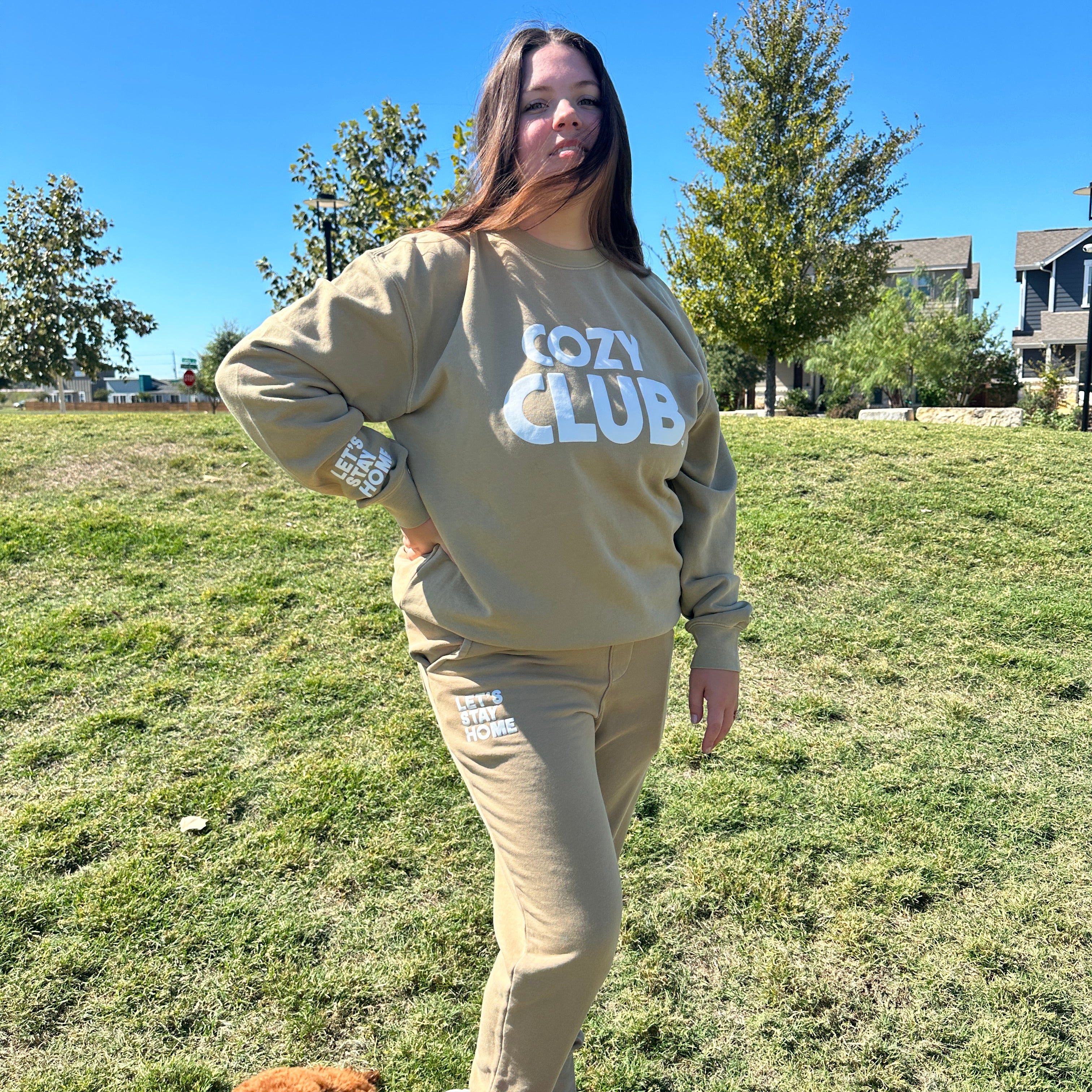 Let's Stay Home Sweats in sandstone with a matching Cozy Club crewneck, worn by a model on a lawn with a small brown dog