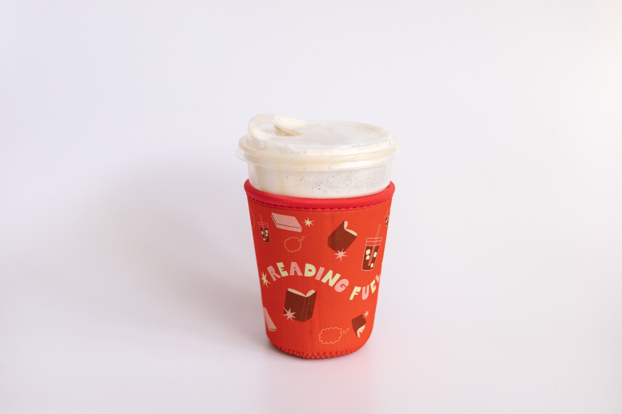 Reading Fuel Coffee Sleeve in red with book and iced coffee pattern on a plastic cup against a white background