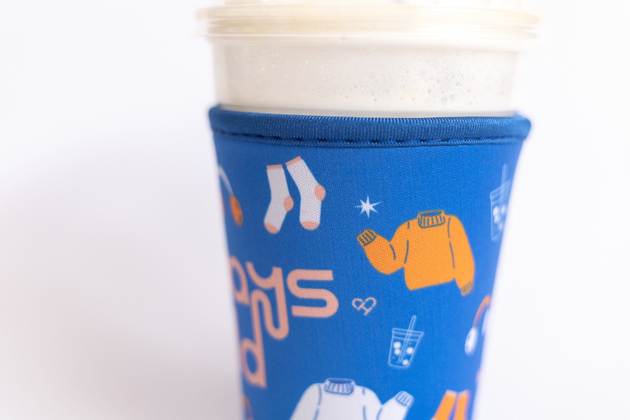 Always Cold Coffee Sleeve, close up of blue sleeve printed with socks, orange sweater and iced drink icons