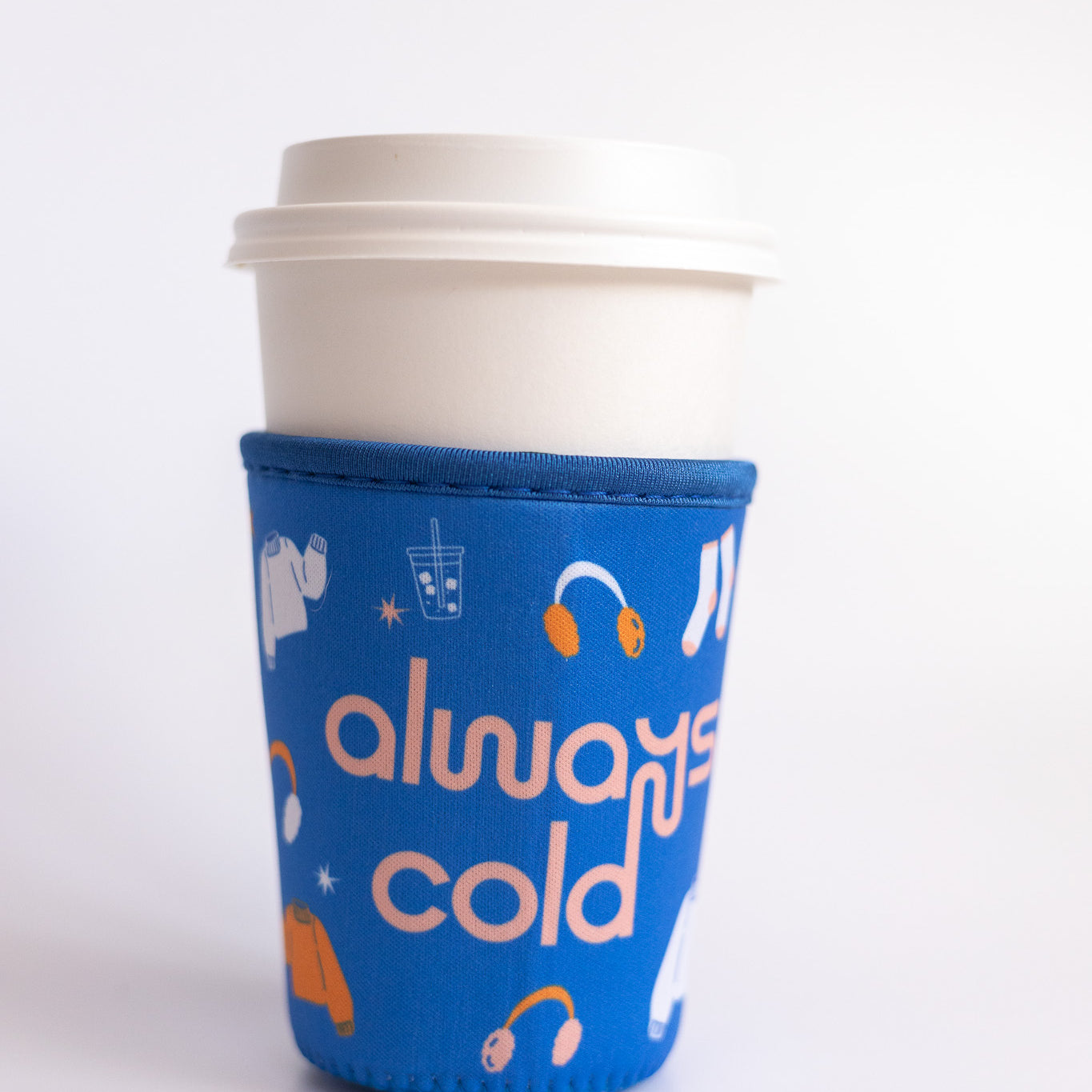 Always Cold Coffee Sleeve, blue sleeve with peach always cold text, earmuffs and sweater icons on a white coffee cup