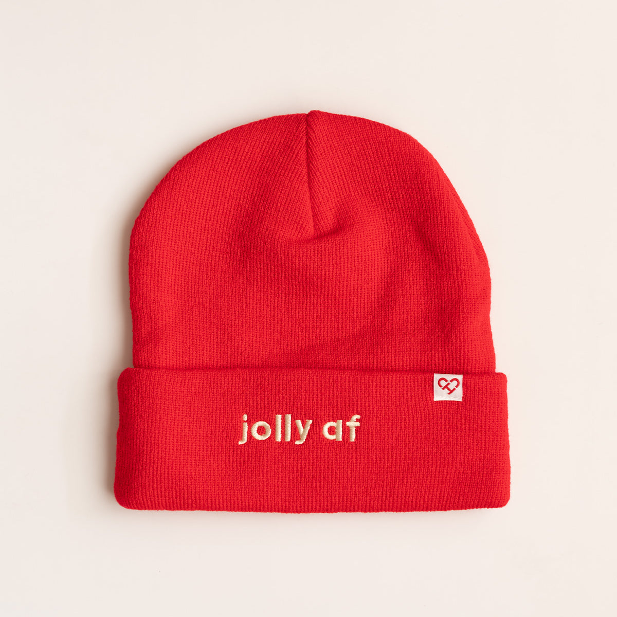 Jolly AF Beanie, red cuffed knit beanie with cream embroidered jolly af lettering and a small heart logo tag