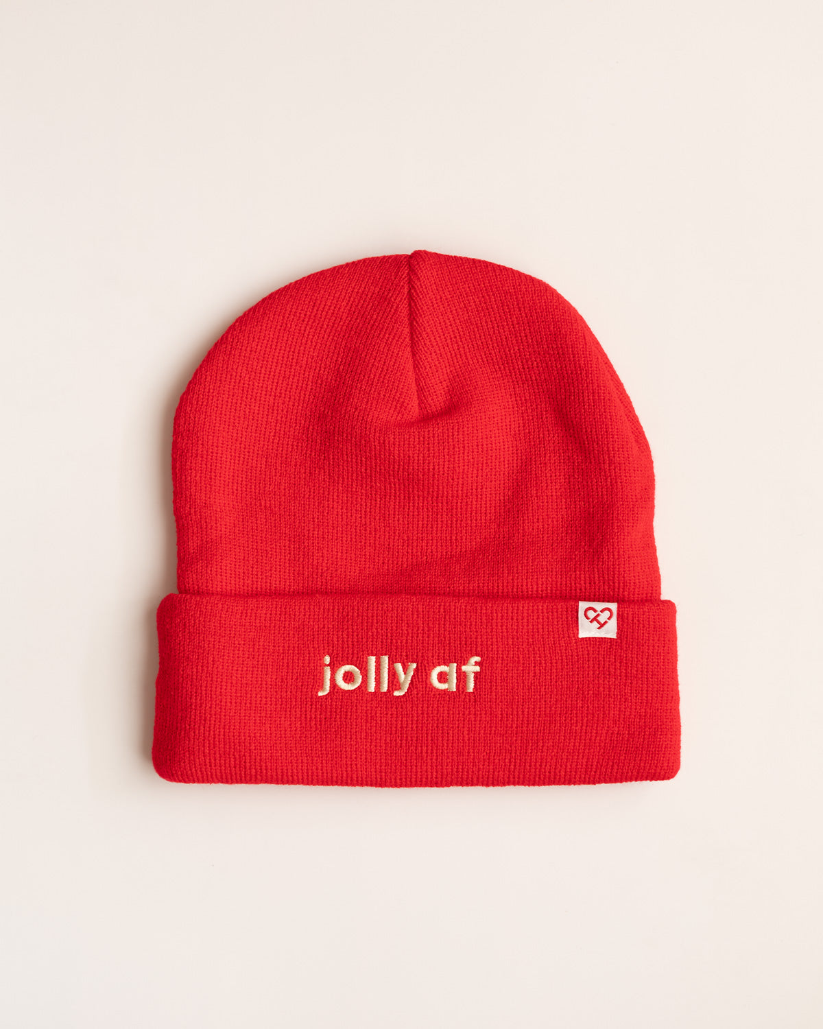 Jolly AF Beanie, red cuffed knit beanie with cream embroidered jolly af lettering and a small heart logo tag