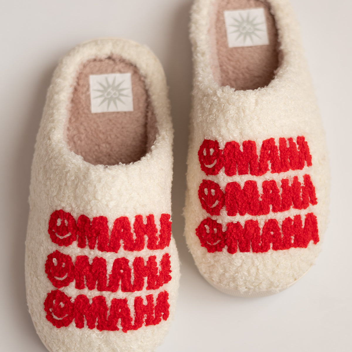 DOORBUSTER Omaha Smiley Slippers, cream sherpa slippers with red tufted smiley faces and Omaha repeated three times