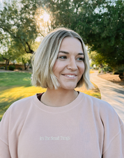 Appreciate Small Things Crew, smiling model outdoors in a peach crewneck with It's The Small Things chest text