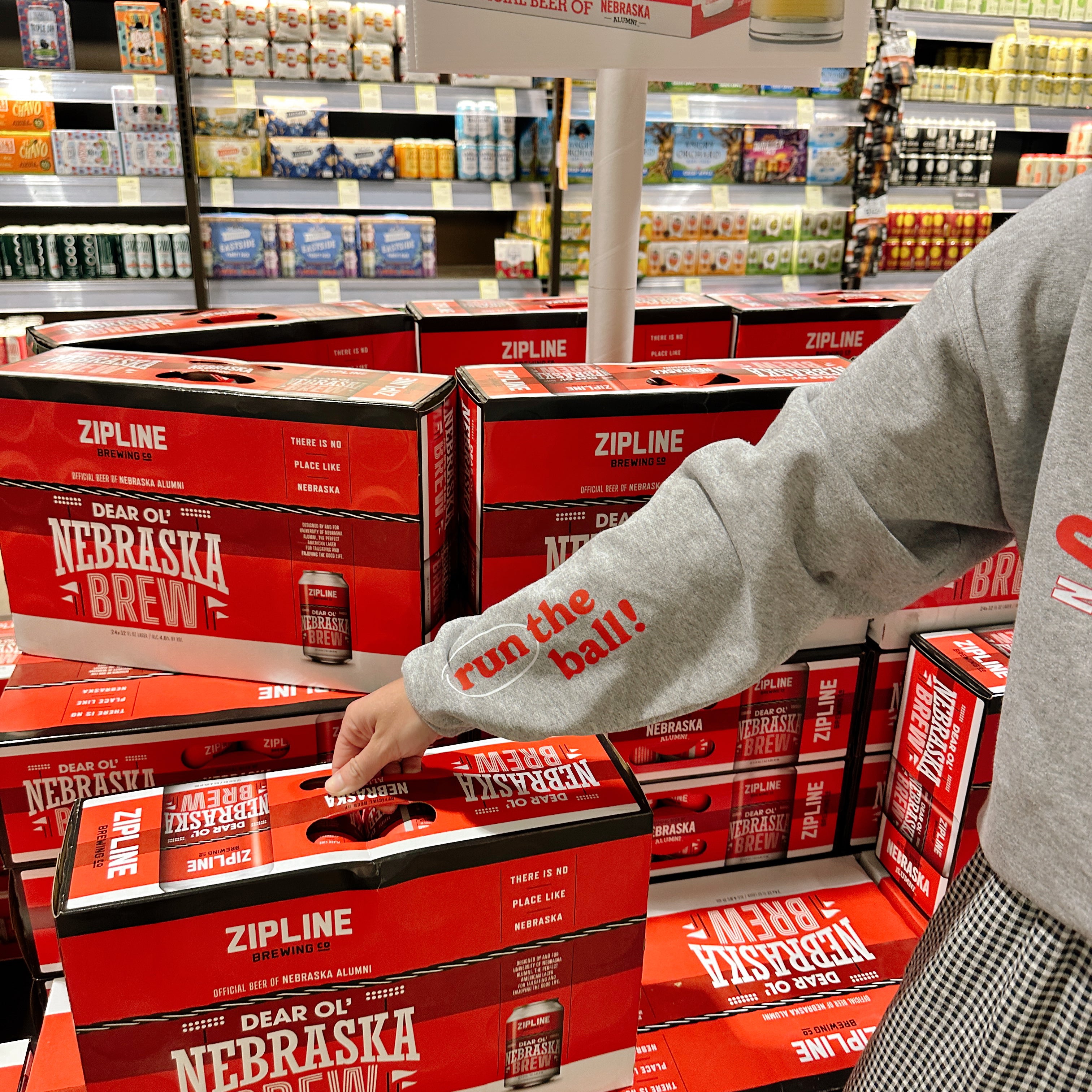 Nebraska Gameday Crew sleeve detail, red run the ball! print on the gray sleeve reaching for a Nebraska Brew case