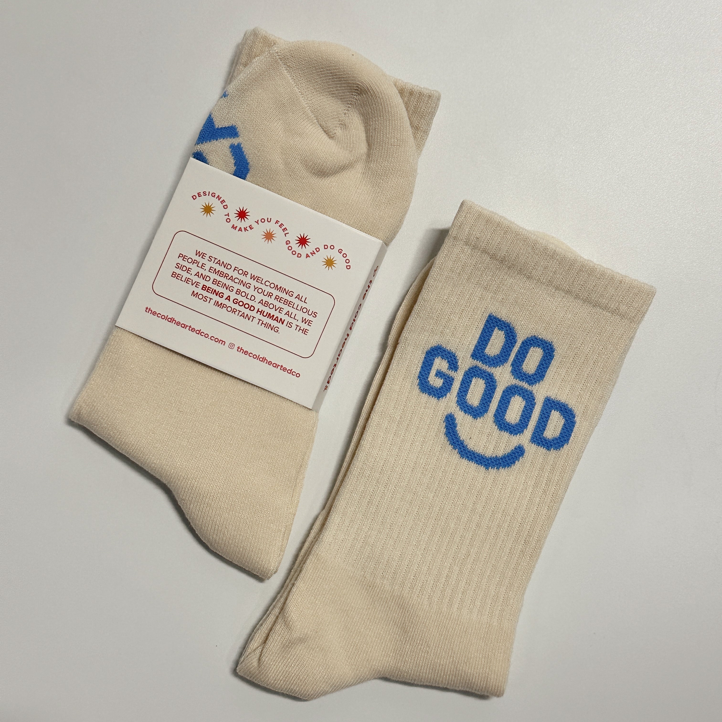 Do Good Socks, cream crew sock with blue Do Good smiley lettering beside a pair in a mission statement band