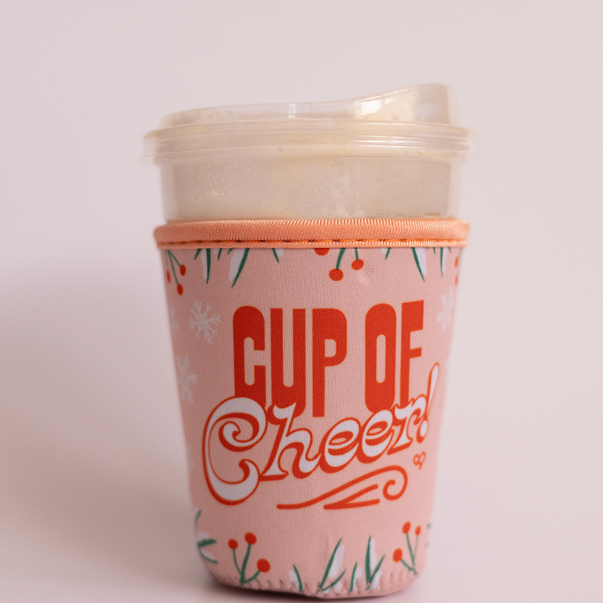 Cup of Cheer Coffee Koozie, pink sleeve with red and white Cup of Cheer lettering and holly berries on an iced drink